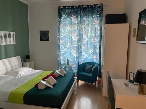 Camera Verde della AD Trastevere Guest House a Roma con letto bianco, poltrona turchese, tende floreali e vista sulla città