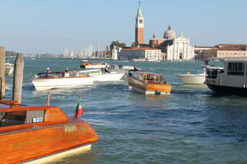 Colorful boats on Venice lagoon with San Giorgio Maggiore basilica and sailboats, near Covo del Pirata