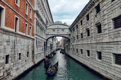 Venice canal with gondolas passing under the Bridge of Sighs, historic architecture of Covo del Pirata location