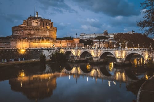 Castel Sant'Angelo and illuminated bridge over Tiber River at dusk in Rome, near Trastevere