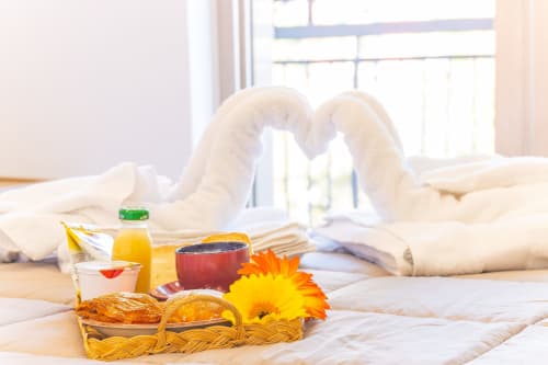 Desayuno acogedor en la cama del B&B Museo19 Nápoles con pastelería, zumo y flor amarilla en habitación luminosa