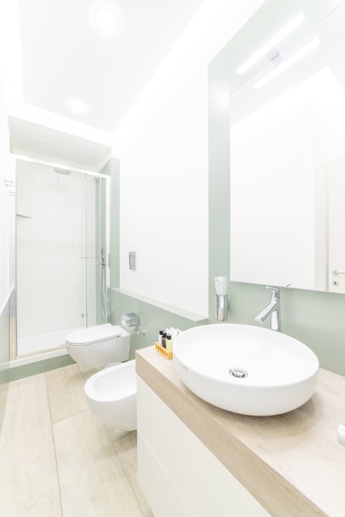 Bagno moderno in Camera Superior Museo19, Napoli con lavabo bianco, toilette, doccia, parete verde e grande specchio