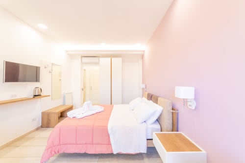 Deluxe room at Museo19 boutique hotel in Naples with pink accents, wooden furniture, and modern amenities