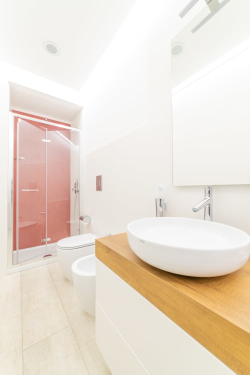 Modern bathroom at Museo19 Naples with white oval sink, wooden vanity, red-framed shower enclosure, and contemporary fixtures