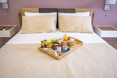 Museo19 Naples deluxe room with breakfast tray on bed, cream pillows, and purple accent wall