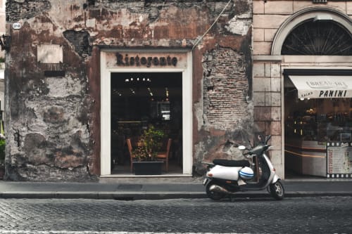 Historic Ristorante storefront in Trastevere, Rome with weathered brick facade and white Vespa scooter parked outside