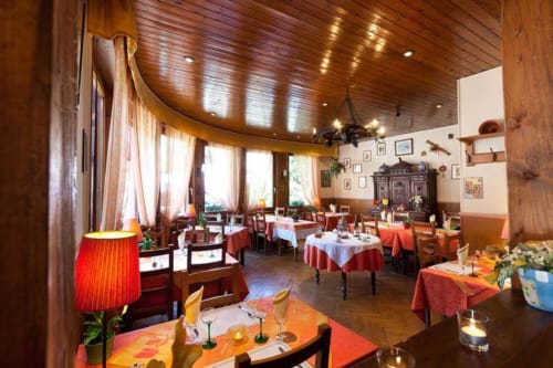 Élégante salle à manger de la Résidence Soansa du Géradmer à Soultzeren avec plafond en bois, tables rondes, linges rouges et ambiance chaleureuse