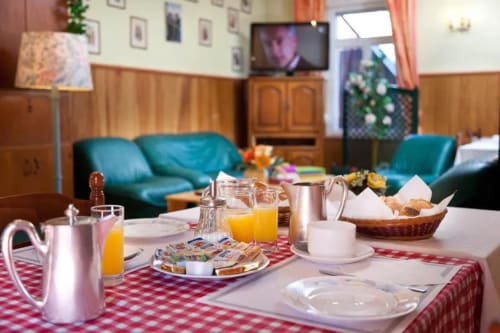 Salle de petit-déjeuner à la Résidence Soansa du Gerardmer avec nappe à carreaux rouges, viennoiseries, jus et coin détente turquoise