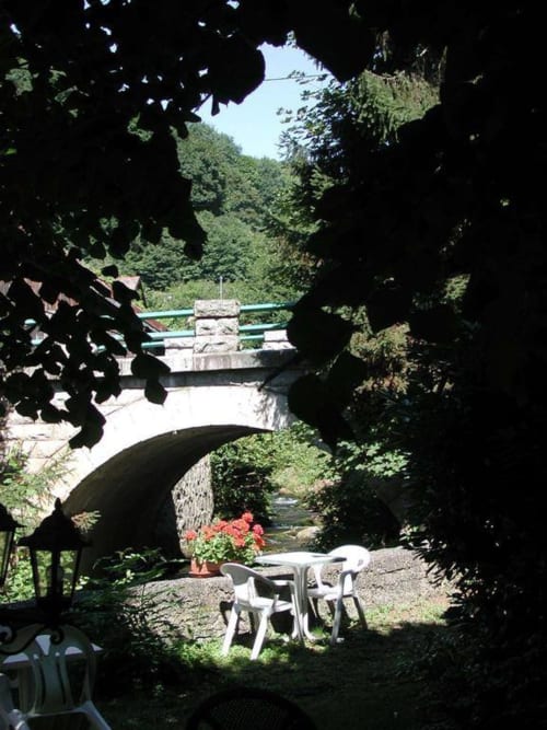 Coin de détente ombragé avec passerelles et arche en pierre à la Résidence Soansa du Gerardmer, Soultzeren