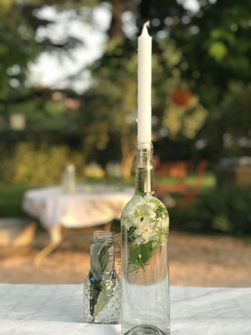 Table élégamment dressée au Campagne d'Albert BnB à Marseille avec bougie blanche dans une bouteille de vin et jardin en arrière-plan