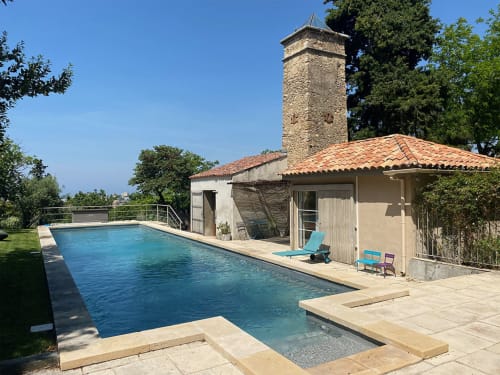 Vue de la piscine de Campagne d'Albert à Marseille avec tour en pierre, transats et cabana au bord de l'eau