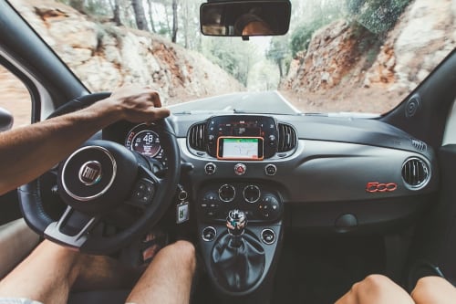 Fiat 500 interior dashboard with driver's hands on steering wheel, mountain road view, Naples Italy