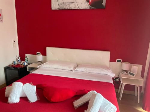 Camera da letto rossa luminosa presso AD Trastevere Guest House a Roma con testata bianca, accenti rosa e vista sulla città