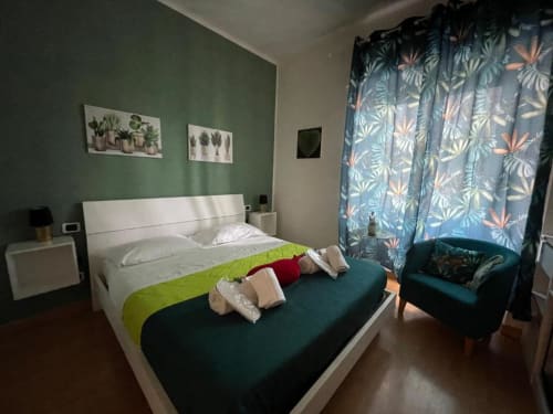 Green Room della AD Trastevere Guest House a Roma con letto bianco, accenti smeraldo e decorazioni botaniche