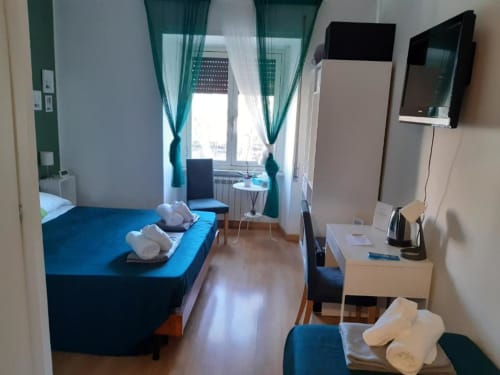 Camera moderna all'AD Trastevere Guest House di Roma con letti gemelli, tende verdi, scrivania e vista sulla città