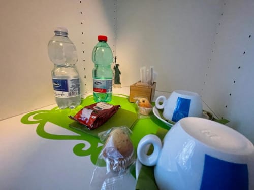 Servizi della stanza verde presso AD Trastevere Guest House a Roma con bottiglie, articoli da toilette e snack su un tavolo decorativo