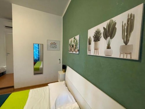 Camera verde presso AD Trastevere Guest House a Roma con arte murale di cactus, letto bianco e arredamento moderno