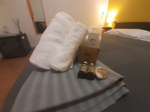 Servizi della camera d'hotel presso AD Trastevere Guest House Roma: asciugamani bianchi, articoli da toilette e kit igienico dentale sul letto