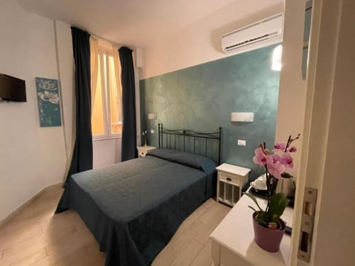 Cozy bedroom at AD Trastevere Guest House Rome with dark bed, green accent wall, orchids, and air conditioning