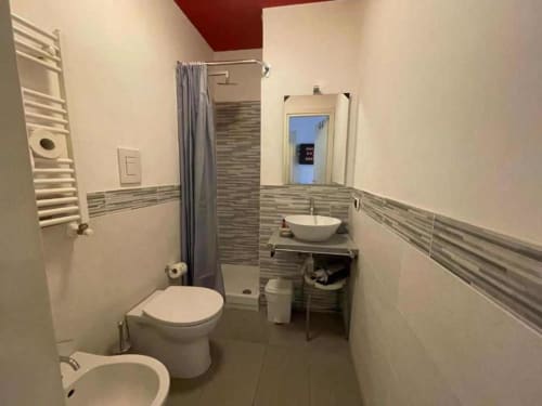 Bagno moderno nella Red Room dell'AD Trastevere Guest House a Roma, con wc, lavabo a bacinella, doccia e piastrelle a righe