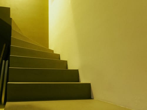 Escalier contemporain aux marches sombres et murs jaunes à La Guirtelle, chambre d'hôtes à Lainsecq, France