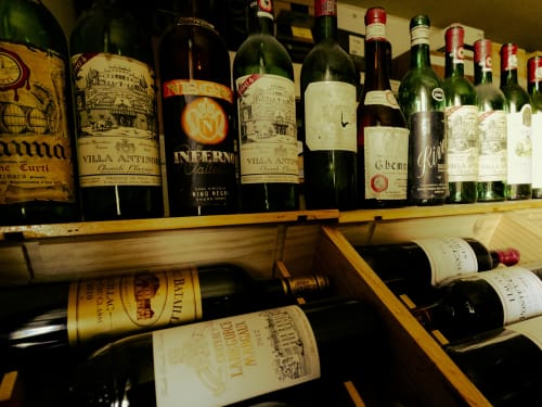 Wine collection display at La Guirtelle B&B in Lainsecq, France featuring vintage bottles on wooden shelves
