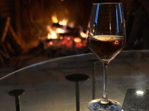 Glass of red wine by fireplace at La Guirtelle B&B in Lainsecq, France, cozy evening ambiance