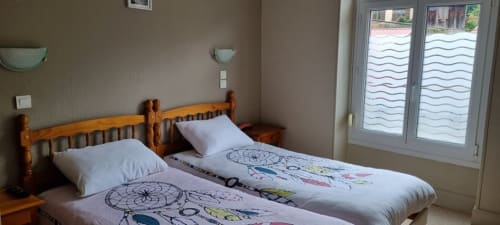 Chambre twin avec lits en bois, literie blanche et draps à motifs à la Résidence Soansa du Gérardmer à Soultzeren