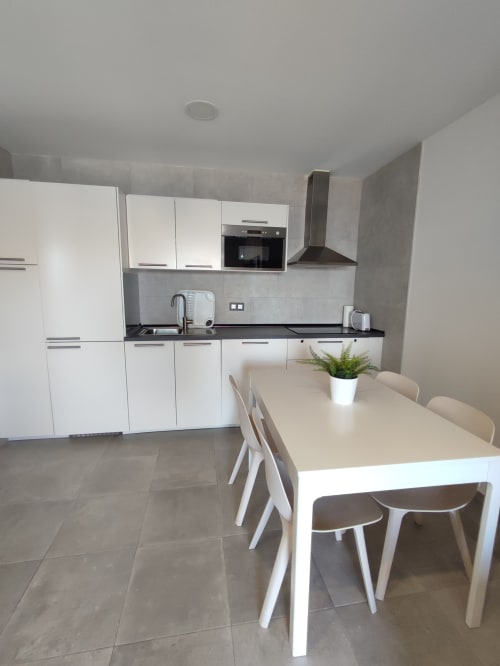 Cocina moderna blanca con mesa de comedor en el apartamento El Faro De Los Genoveses en San José, Almería