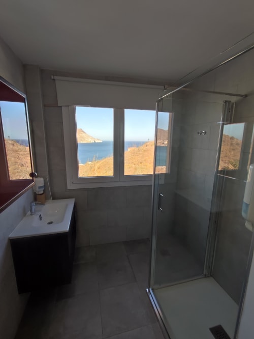 Baño moderno con ducha abierta con vistas a acantilados costeros y mar Mediterráneo en El Faro Los Genoveses, Almería