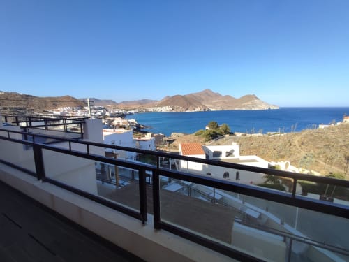 Vista desde el balcón de la costa de San José, Almería, con el Mar Mediterráneo turquesa y edificios encalados en el paisaje árido