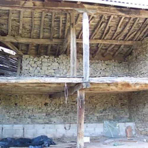 Interior rústico con vigas de madera expuesta del hotel Casa Lafuente en Lukiano, Araba, mostrando arquitectura tradicional y muros de piedra