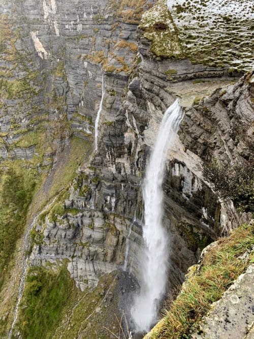Cascada cayendo por acantilados rocosos cubiertos de musgo cerca de Casa Lafuente en Lukiano, Araba, España