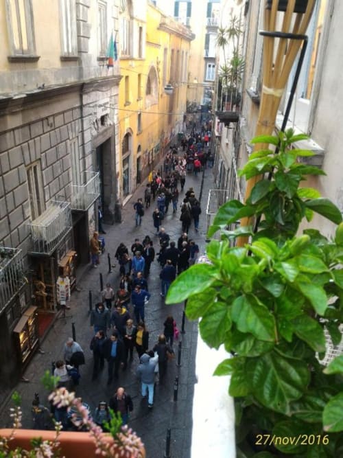 Aerial view of bustling Naples street from B&B Il Conservatorio balcony with historic buildings and pedestrians below