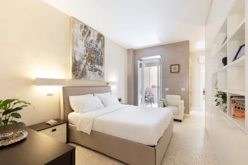 Suite deluxe di Petra Apartments a Roma con letto matrimoniale, illuminazione moderna e accesso a balcone con vista sulla città