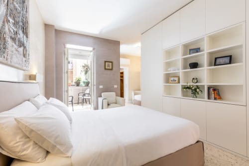 Camera da letto moderna e luminosa negli Appartamenti Petra Roma con letto bianco, scaffalature integrate e balcone con vista sulla città