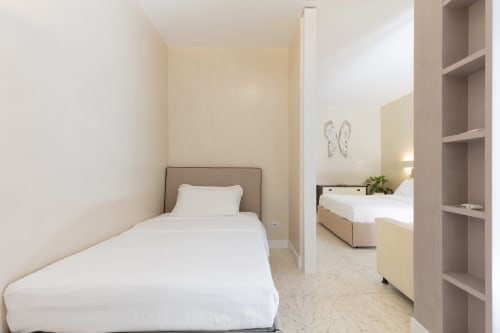 Camera deluxe Petra Apartments a Roma con letti gemelli, biancheria bianca e design minimalista moderno con elementi