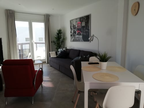 Moderno apartamento en El Faro De Los Genoveses con zona de comedor, sofá negro, silla roja y balcón con vistas al mar en San José