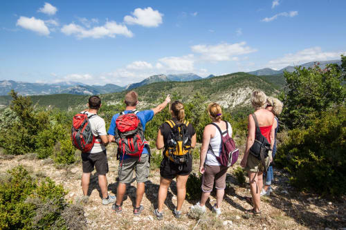 Group of hikers with backpacks overlooking mountainous landscape near Grignan, France