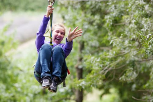 Child zip-lining through forest canopy near Grignan, France adventure activities