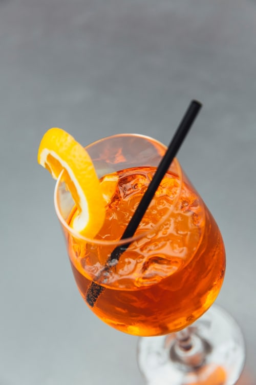 Orange aperitif cocktail with lemon slice and straw at Museo19 boutique hotel in Naples