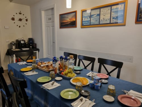 Dining room at B&B Il Conservatorio in Naples with blue tablecloth, place settings, fresh fruit, and decorative wall art