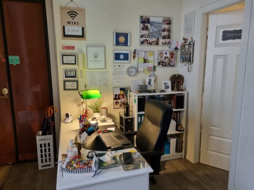 Cozy home office workspace at B&B Il Conservatorio in Naples with desk, computer, green lamp, and personal memorabilia on
