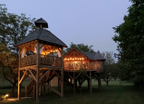 Illuminated wooden treehouse structure at Domaine De Campagnac in Carsac-Aillac, France, evening garden view