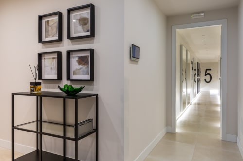 Corridoio moderno di Casa Lounge Istria a Cagliari con opere d'arte incorniciate, libreria espositiva e passaggio aperto verso la camera 5