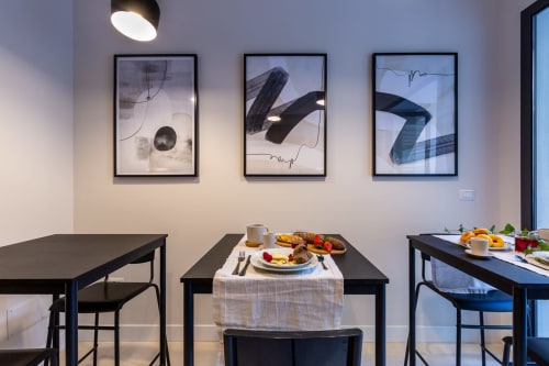 Elegante area ristorazione presso Casa Lounge Istria a Cagliari con tavoli neri, colazione gourmet e arte contemporanea alle pareti