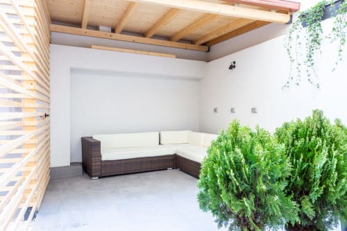Terrazza lounge moderna a Casa Lounge Istria, Cagliari con divano componibile in rattan, travi in legno e lussureggiante vegetazione