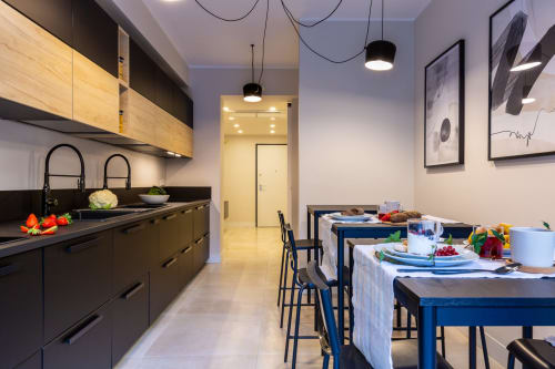 Moderna cucina e zona pranzo di Casa Lounge Istria a Cagliari con pensili neri, tavolo blu e tavola apparecchiata