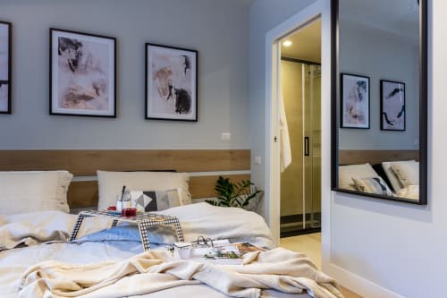 Camera moderna di Casa Lounge Istria a Cagliari con testata in legno, armadio a specchi e opere d'arte incorniciate.
