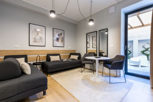 Moderna zona lounge di Casa Lounge Istria a Cagliari con divani neri, lampade a sospensione e porte in vetro che si aprono sul patio